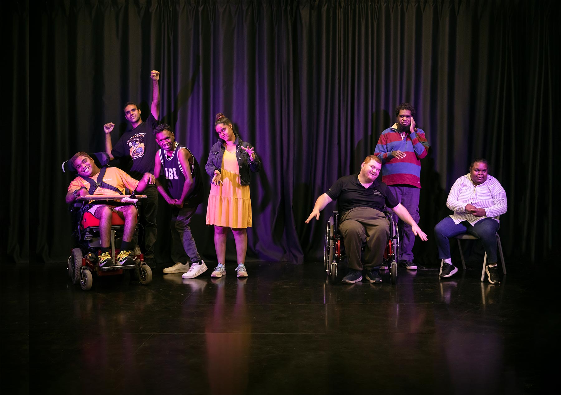 Groups of four and three people on a theatre stage in front of a dark curtain