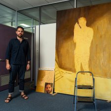 Christopher Bassi standing in an empty office next to a large yellow painting