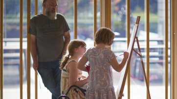 Two children drawing at an easel in the Gordon Darling Hall