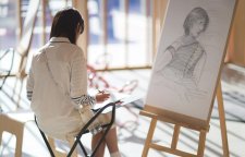 A person drawing on paper in front of an easel A person drawing on paper in front of an easel