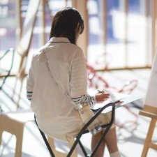 A person drawing on paper in front of an easel A person drawing on paper in front of an easel