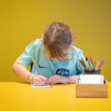 A child drawing at a yellow table