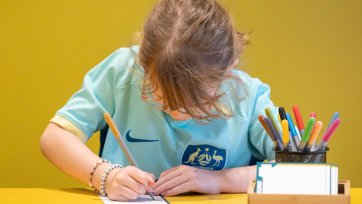 A child drawing at a yellow table