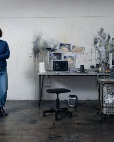 Fiona McMonagle standing in her studio with paint splatters on the white walls