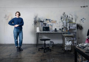 Fiona McMonagle standing in her studio with paint splatters on the white walls