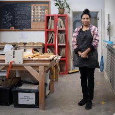 Naomi Hobson standing next to a wooden table and metal sink in her studio