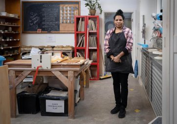 Naomi Hobson standing next to a wooden table and metal sink in her studio