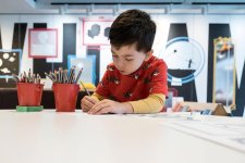 A boy drawing on paper with a pencil