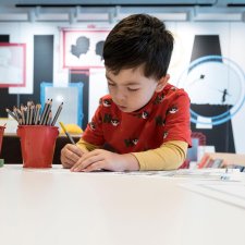 A boy drawing on paper with a pencil