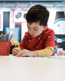 A boy drawing on paper with a pencil