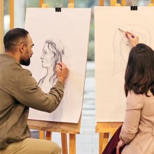 Two people drawing at easels Two people drawing at easels