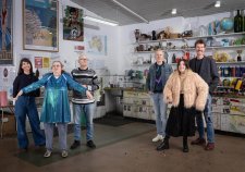 Two grounps of three people standing in a studio with walls and shelves filled with artworks