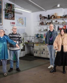 Two grounps of three people standing in a studio with walls and shelves filled with artworks