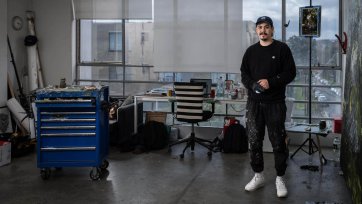 Abdul Abdullah in his studio with large windows overlooking a suburban street