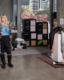 Tarryn Gill standing in her studio next to a sculpture on a white plinth