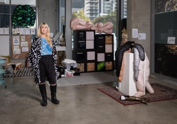 Tarryn Gill standing in her studio next to a sculpture on a white plinth
