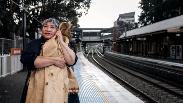 Latai Taumoepeau holding a blanket to her body while standing on the platform at a train station