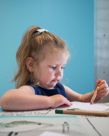 A child drawing on paper at a table A child drawing on paper at a table