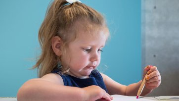 A child drawing on paper at a table