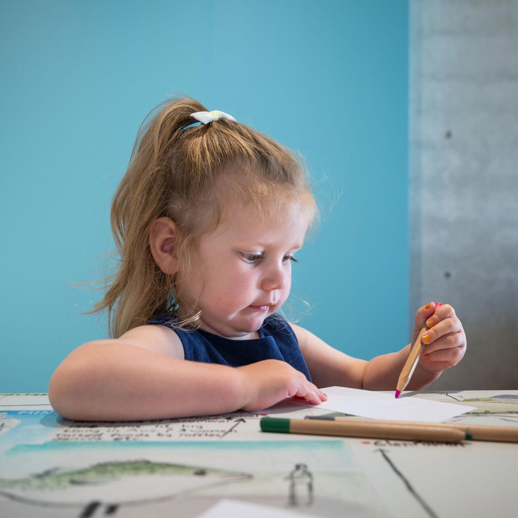 A child drawing on paper at a table