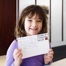 A girl with a postcard in the Brack x McKenna Creative Space