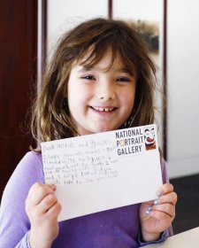 A girl with a postcard in the Brack x McKenna Creative Space