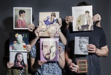 Hands holding a series of books in front of people, hiding their faces