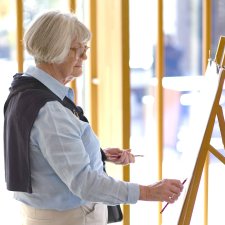 A person drawing with a pencil at an easel A person drawing with a pencil at an easel