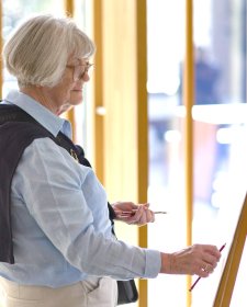 A person drawing with a pencil at an easel A person drawing with a pencil at an easel