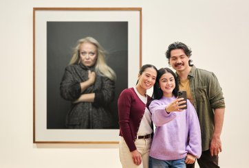 People using a phone to take a photo in front of an artwork
