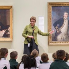 A teacher with a group of children in front of a painting in a gallery