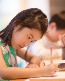 A child drawing at a wooden table A child drawing at a wooden table
