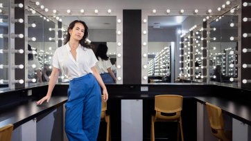 Amrita Hepi standing in front of a dressing room mirror surrounded by lights