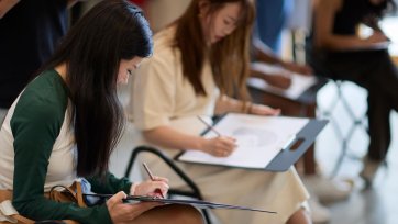 People drawing on paper notepads