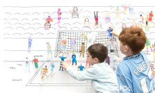 Children placing paper cutouts of athletes on a soccer wall scene