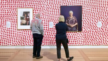 Two people viewing artworks in the In Bloom exhibition