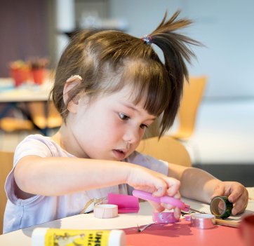 A hard of hearing participant enjoying creative making during story time for children and families