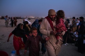 A family hurries to join a group granted access to the north-western gate of the airport, 2021 Andrew Quilty