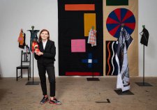 Sally Smart standing in her wooden floored studio holding a puppet