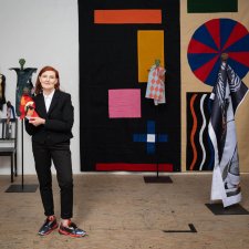 Sally Smart standing in her wooden floored studio holding a puppet