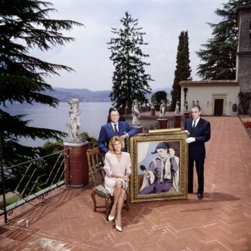 Baron and Baroness Thyssen-Bornemisza pose on the terrace of Villa Favorita with Picasso's 1923 "Harlequin with a Mirror"
